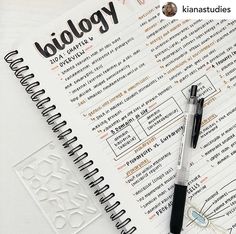 a notebook and pen sitting on top of a paper with the words biology written in it