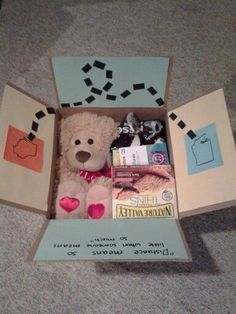 a teddy bear sitting inside of a box on the floor with other items in it