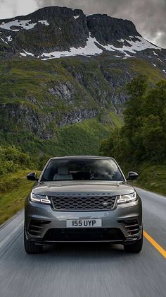 the front end of a grey range rover driving down a mountain road