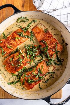 salmon with cream sauce in a skillet on a wooden table