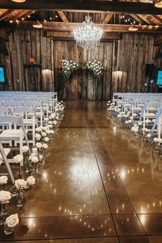 an indoor wedding venue with white chairs and chandeliers