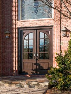 the front door to a brick building with two glass doors and steps leading up to it