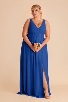 a woman in a blue dress is standing with her hands on her hips and looking at the camera