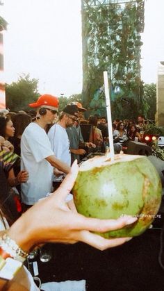 a person holding up a green fruit in front of a crowd