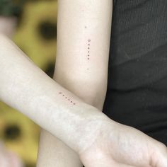 two people with matching tattoos on their arms, one is holding the other's arm