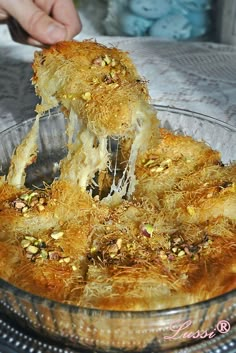 a person is taking some food out of a glass dish on top of a table