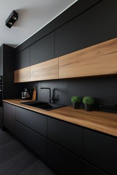 a kitchen with black cabinets and wooden counter tops, along with potted plants on the wall