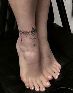 a woman's foot with a tattoo on it and beads hanging from the ankle