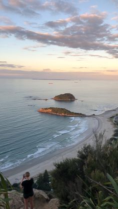 a woman standing on top of a cliff overlooking the ocean