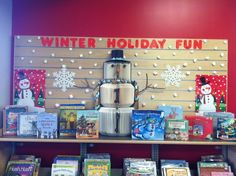 a book shelf with books and a coffee pot on it in front of a sign that says winter holiday fun