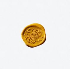 a yellow wax stamp with a flower design on the front and back of it's face