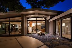 a modern home at night with lights on the front door and patio in the background