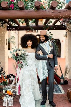 a man and woman standing next to each other in front of an arch with flowers