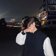 a man standing in front of a building at night with his hand on his face