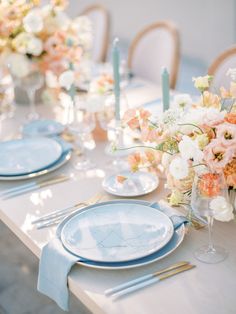 the table is set with blue and white plates, silverware, and floral centerpieces