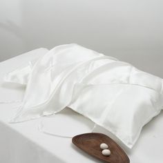 an unmade bed with white sheets and pillows on it's side, next to a wooden spoon