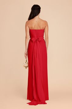 a woman in a red strapless dress is looking back at the camera with her hand on her hip