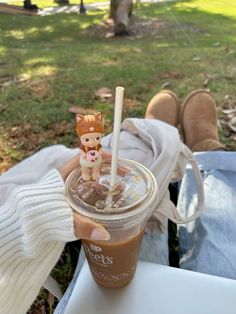 a person holding a cup with a drink in it and a toy animal on top