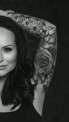 a black and white photo of a woman with tattoos on her arms