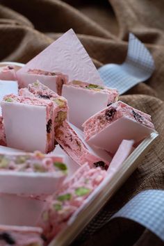 several pieces of cake sitting in a tray on a bed next to a spoon and cloth