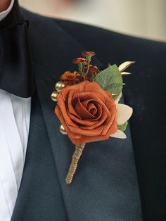 a boutonniere with an orange rose and leaves is worn by a man in a tuxedo