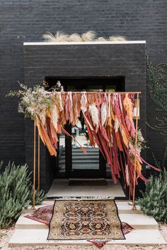 an outdoor area with rugs, plants and hanging decorations on the side of the building