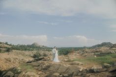 a bride and groom standing on rocks in the desert