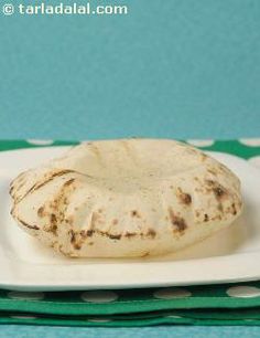 a white plate topped with a piece of food on top of a green and white table cloth