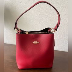 This Stunning Red/ Oxblood Colored Coach Purse Is Made Of Pebbled Leather And Features A Center Zip Compartment, A Small Interior Pocket, And A Snap Closure On Top. The Top Handle Has A 6 3/4” Drop And A Detachable Strap With A 22” Drop For Shoulder Or Crossbody Wear. Dimensions (Approx.): - 8.5” L - 8.5” H - 4” W Red Luxury Bucket Bag With Detachable Handle, Luxury Red Bucket Bag With Detachable Handle, Luxury Red Top Handle Bucket Bag, Red Bucket Bag With Detachable Handle, Red Top Handle Bucket Bag With Detachable Handle, Red Bucket Bag With Detachable Top Handle, Luxury Red Bucket Bag With Detachable Strap, Red Top Handle Bucket Bag For Evening, Designer Red Rectangular Bucket Bag