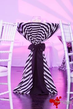 the table is decorated with black and white striped cloths, ribbons, and wine glasses