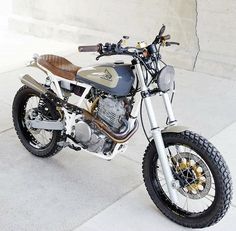 a motorcycle is parked on the sidewalk near a wall and cement floored area with concrete walls in the background