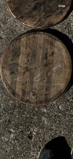 a person standing on the ground next to two wooden barrels that have been turned upside down