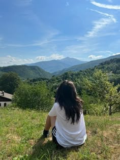 a woman sitting on top of a lush green hillside