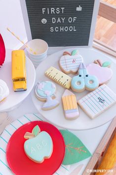 a table topped with lots of cookies and pastries next to a sign that says first day of school