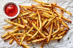 french fries with ketchup and mustard on white paper next to a small bowl of ketchup