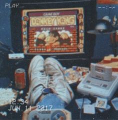 a person's feet resting on a table in front of an old video game