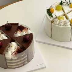 two cakes sitting on top of white plates with cherries and whipped cream toppings