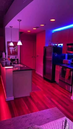 the kitchen is lit up with purple lights and red lighting on the walls, along with stainless steel appliances