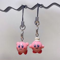 two pink earrings with blue eyes are hanging from a hook