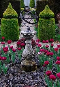 an ornamental fountain surrounded by flowers and bushes