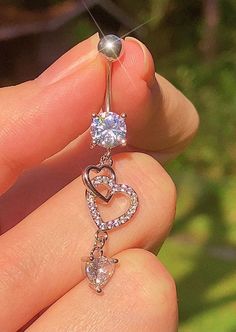 a person holding a heart shaped ring with a diamond on it's side and an arrow in the middle