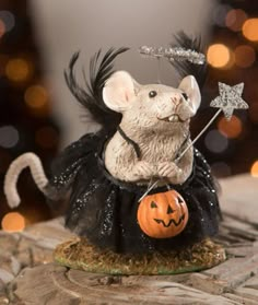 a mouse dressed up as a witch with a pumpkin on it's back and holding a star