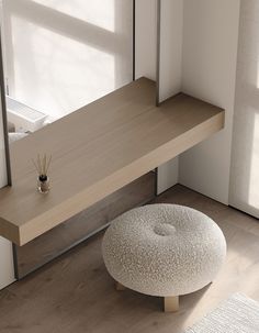 a white ottoman sitting on top of a hard wood floor next to a wooden shelf