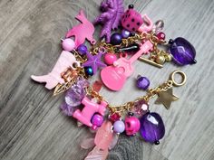 "This beautiful charm bracelet was lovingly made by me. It's got a stainless steel gold colored chain bracelet with varying shades of pink and purple charms. I call these \"toy box\" charm bracelets because many of the charms look like they're right out of a toy box. Lots of fun things to fidget with. This bracelet is made from a mix of vintage and new charms, found objects. ------------------------------- Ghost Candy Creations, be unapologetically you! If you have any problems with your item on Trendy Nickel-free Pink Charm Necklace, Trendy Purple Jewelry For Gift, Personalized Whimsical Pink Bracelet, Personalized Pink Whimsical Bracelet, Pink Whimsical Charm Bracelet For Gift, Pink Vintage Charm Metal Jewelry, Whimsical Personalized Pink Bracelet, Playful Pink Charm Necklaces, Playful Pink Jewelry With Removable Charms