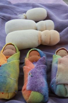 several small stuffed animals are laying on a purple blanket next to two pairs of slippers