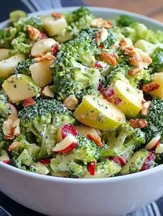 a white bowl filled with broccoli, apples and almonds on top of a table