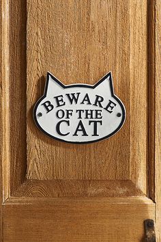 a sign that says beware of the cat on a wooden door