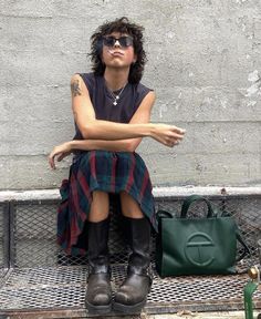 a woman sitting on top of a metal bench next to a handbag and purse