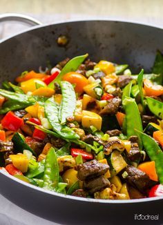 a pan filled with vegetables and meat on top of a table