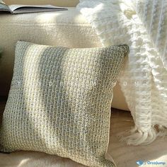 a pillow and blanket on a couch next to a book